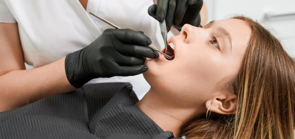 Profesjonalne badanie stomatologiczne w klinice SmileClinic - dentystka w rękawiczkach wykonuje precyzyjne badanie jamy ustnej pacjentki przy użyciu lusterka i zgłębnika diagnostycznego.