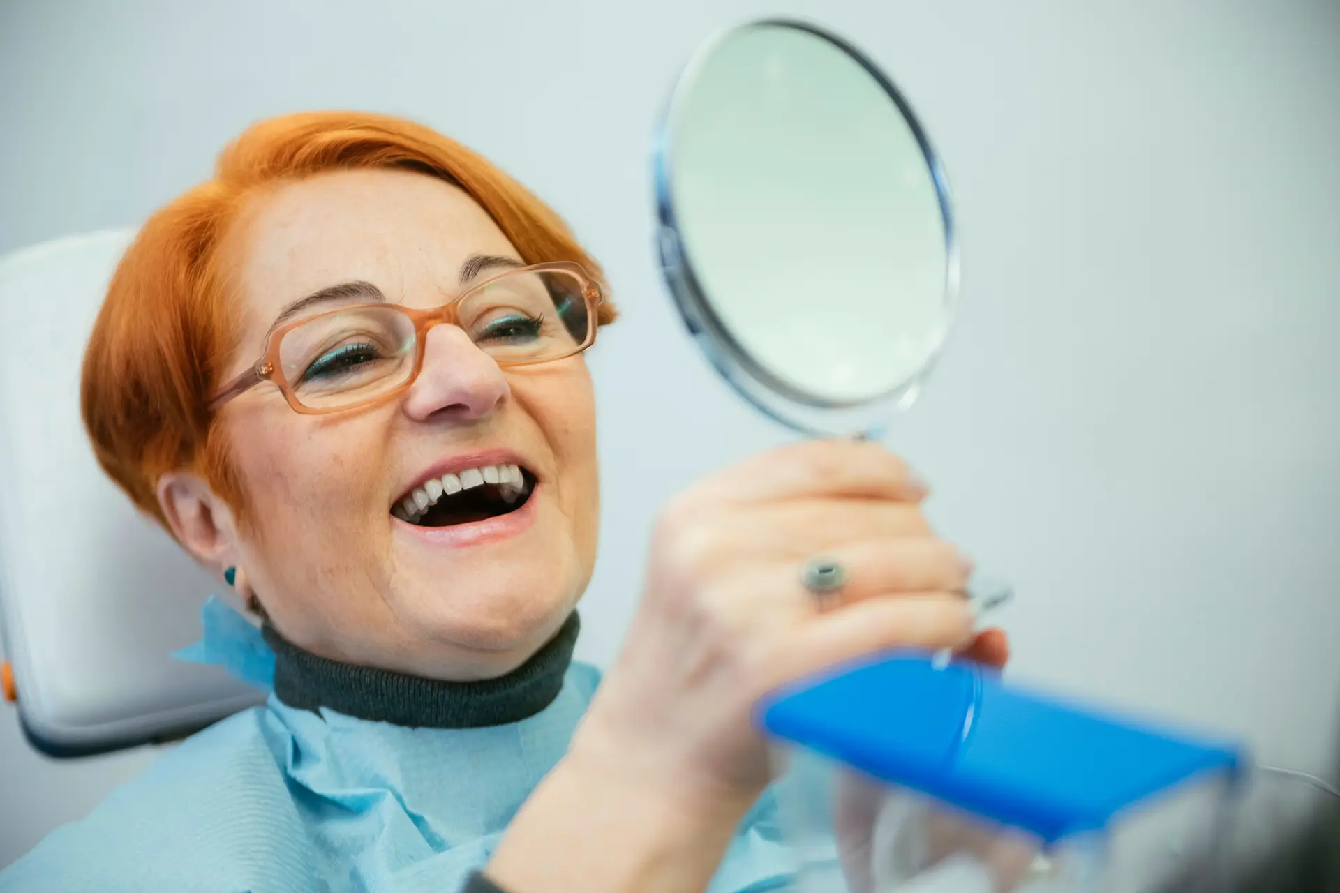 kobieta przeglądająca się w lustrze w gabinecie dentystycznym kobieta przeglądająca się w lustrze w gabinecie dentystycznym