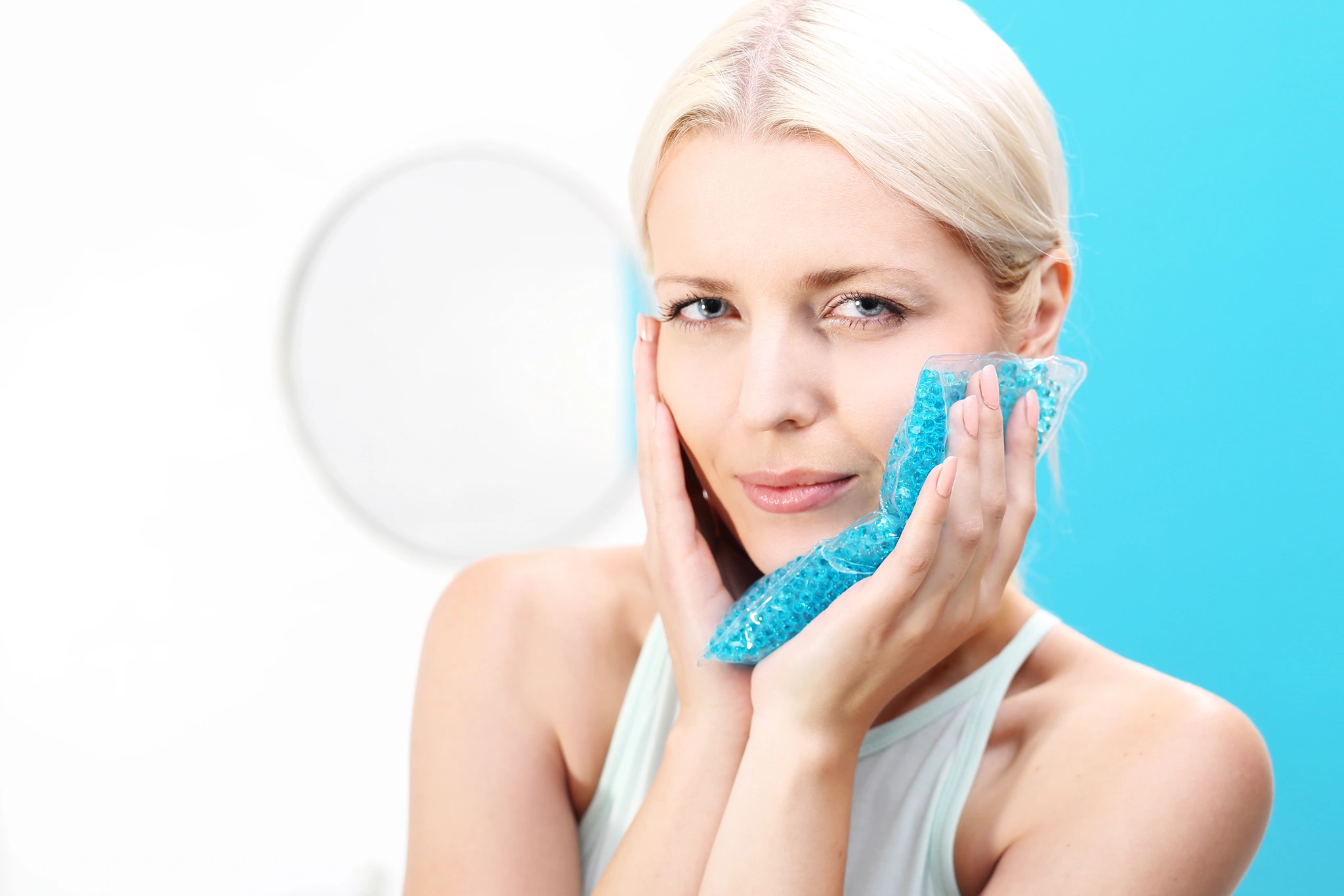 etapy-gojenia-po-wszczepieniu-implantu-2 Kobieta przykładająca zimny kompres do twarzy w trakcie gojenia po wszczepieniu implantu zębowego