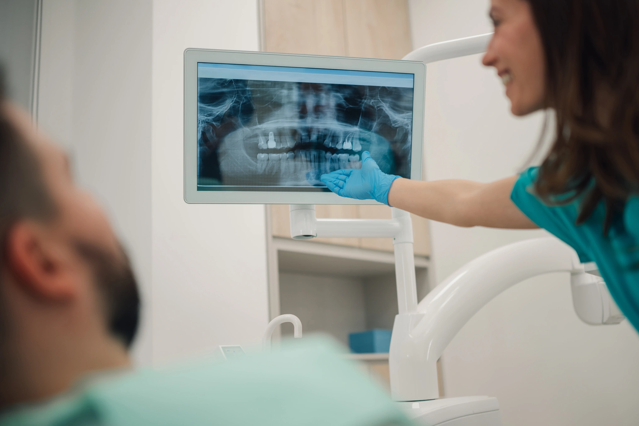 implanty-zebowe-u-pacjentow-z-chorobami-przewleklymi-4 Dentystka omawiająca zdjęcie RTG z pacjentem przed zabiegiem implantologicznym